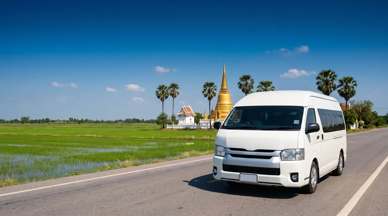 White private transfer van on a country highway through rice fields, a golden temple on the horizon